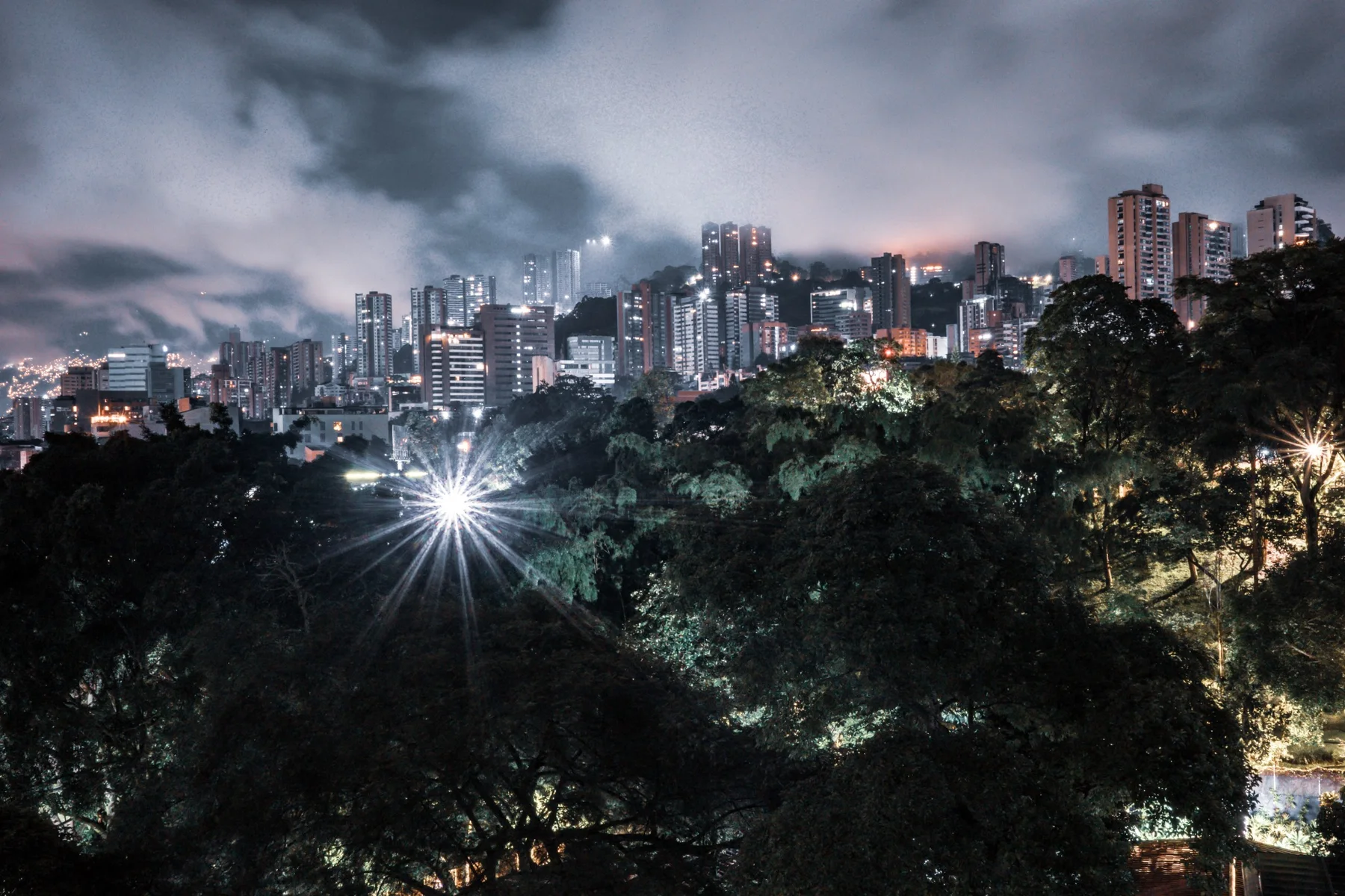 A hillside city under low clouds at night